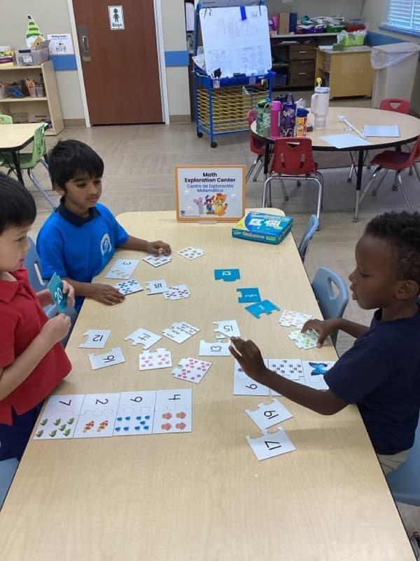 Children at a table counting cards with numbers on them