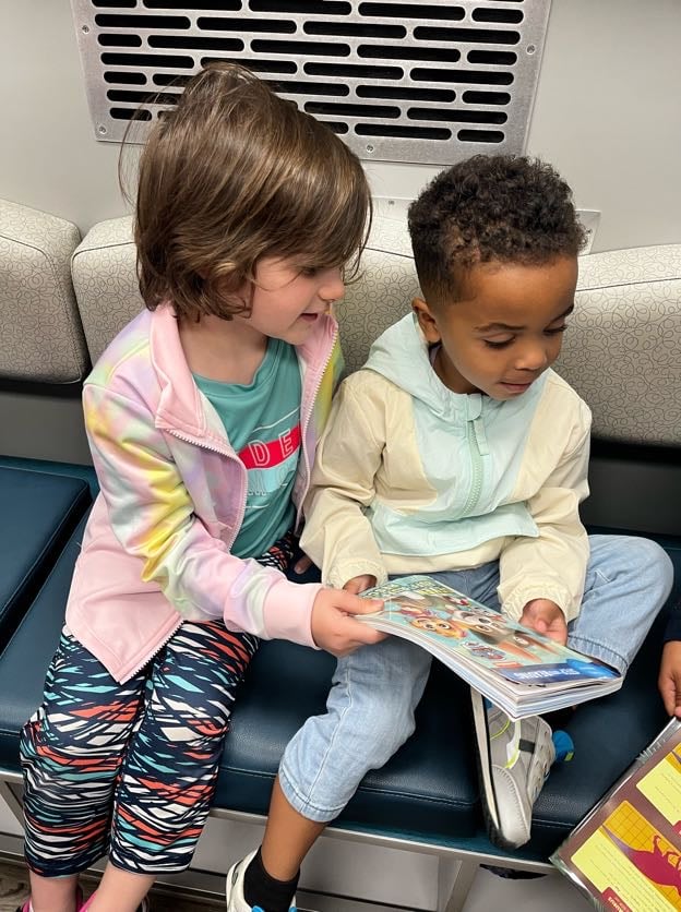 two children sit looking at book