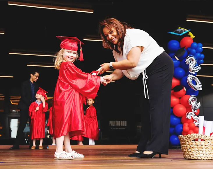 primrose student in cap and gown receiving their graduation diploma on stage