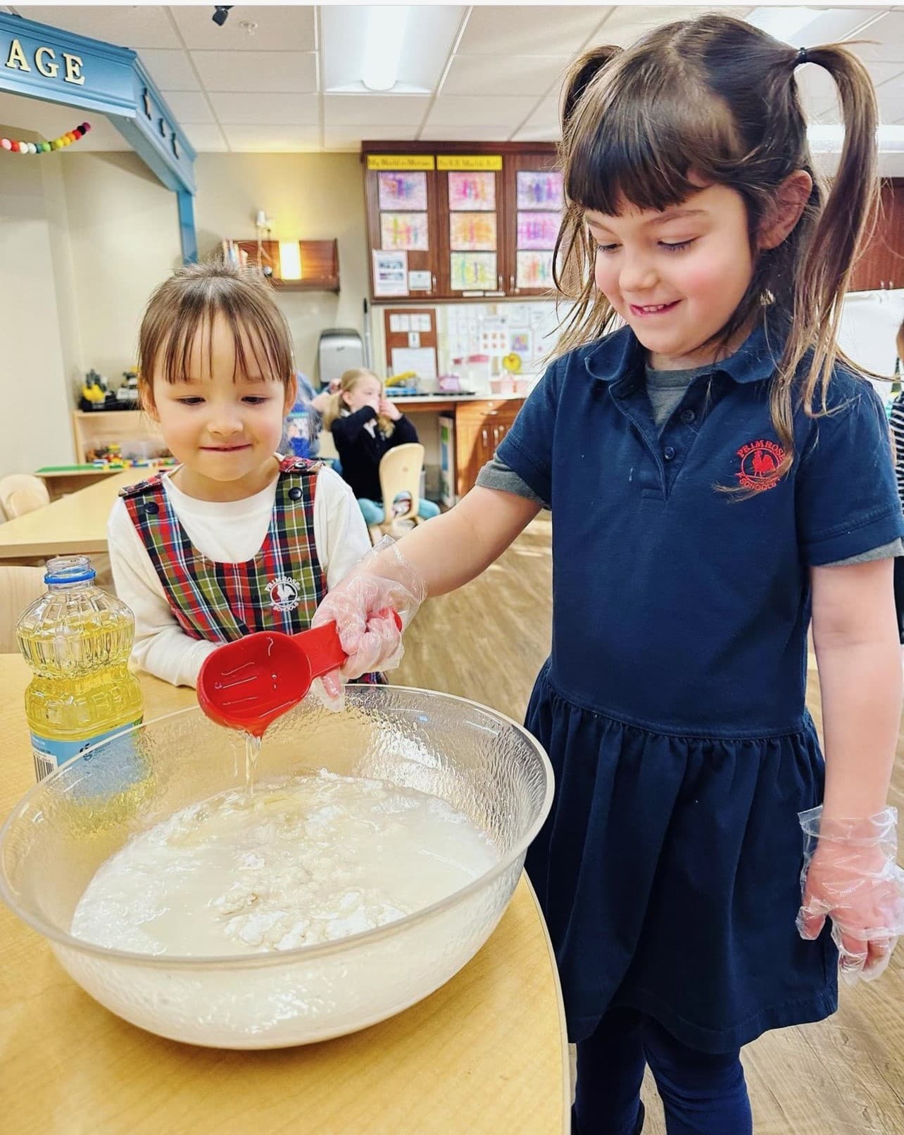Pre-Kindergarten students pouring vegetable oil into flour for activity