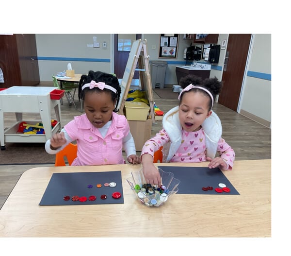 Two girls work on counting with buttons