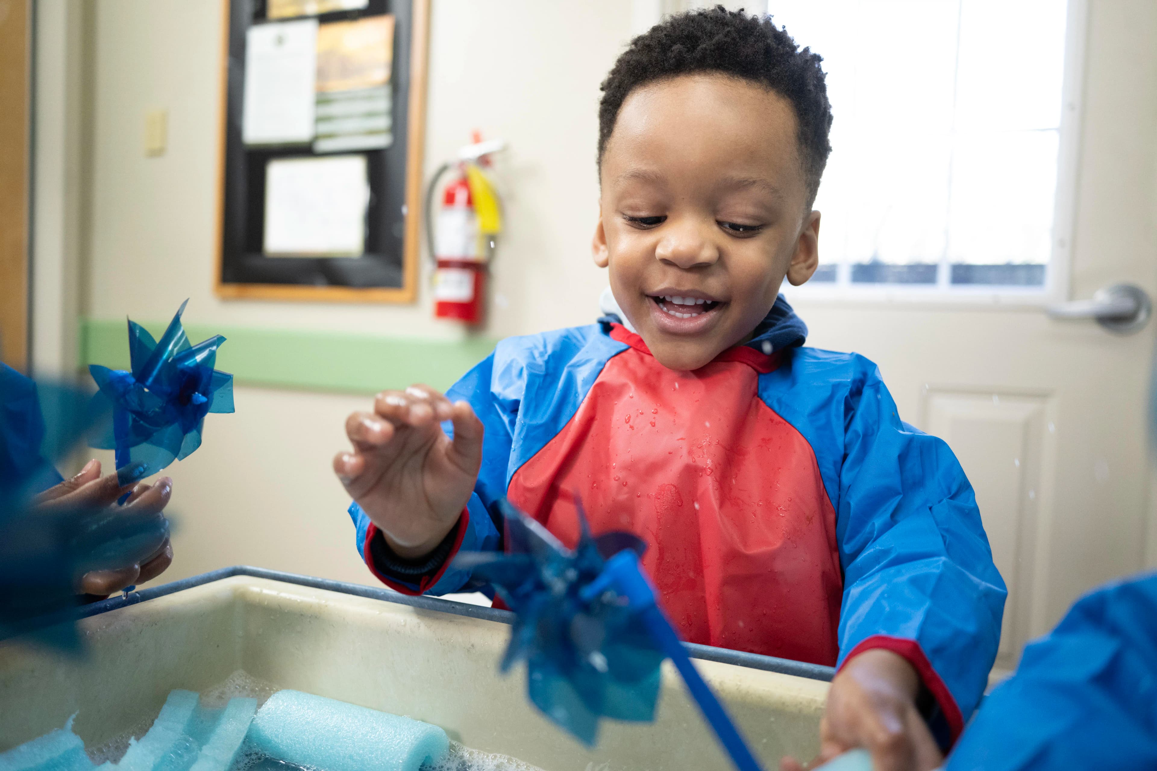 A happy child playing with foam water and wind wheels.