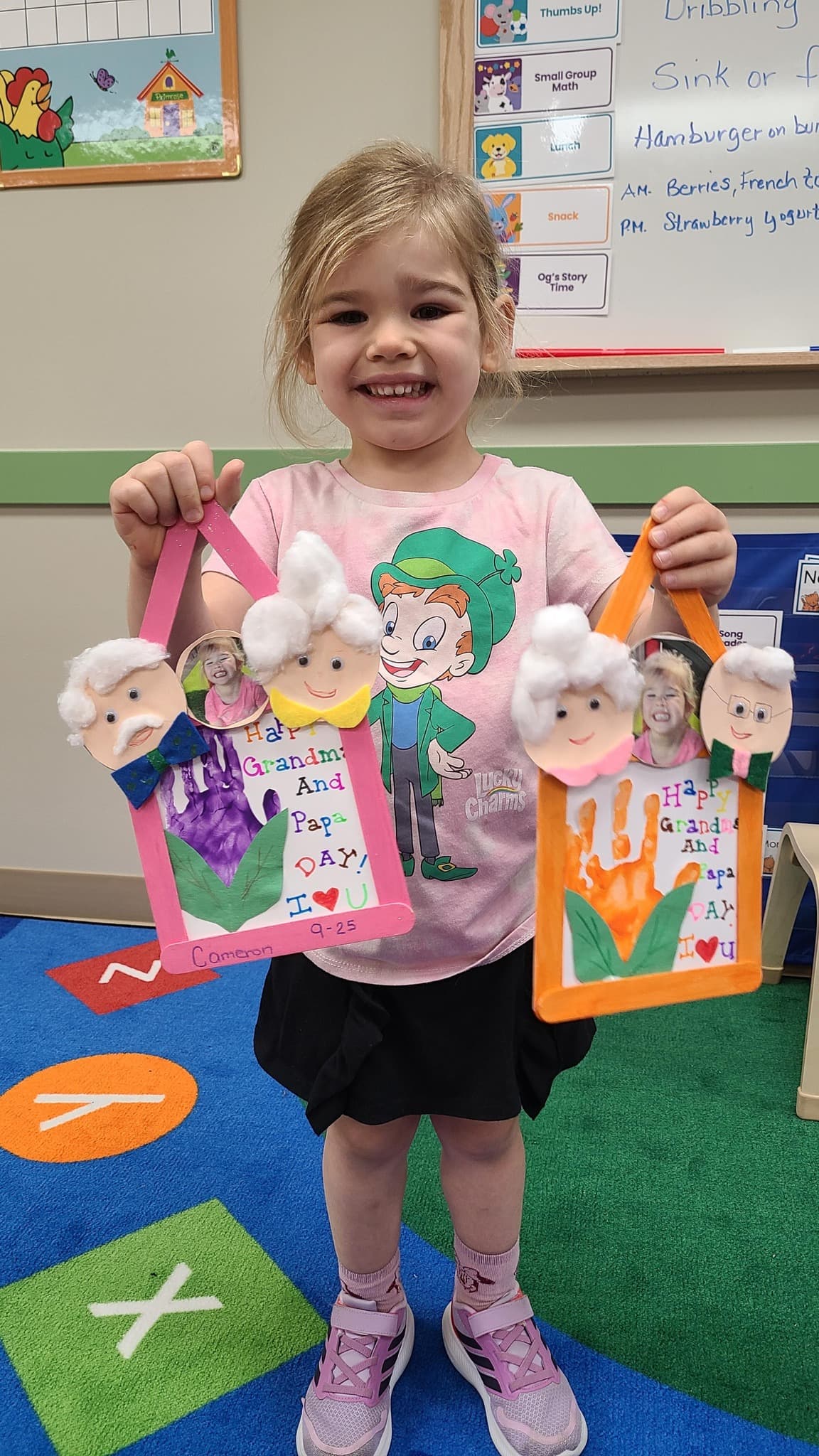 girl with pink shirt holding to grandparents day crafts