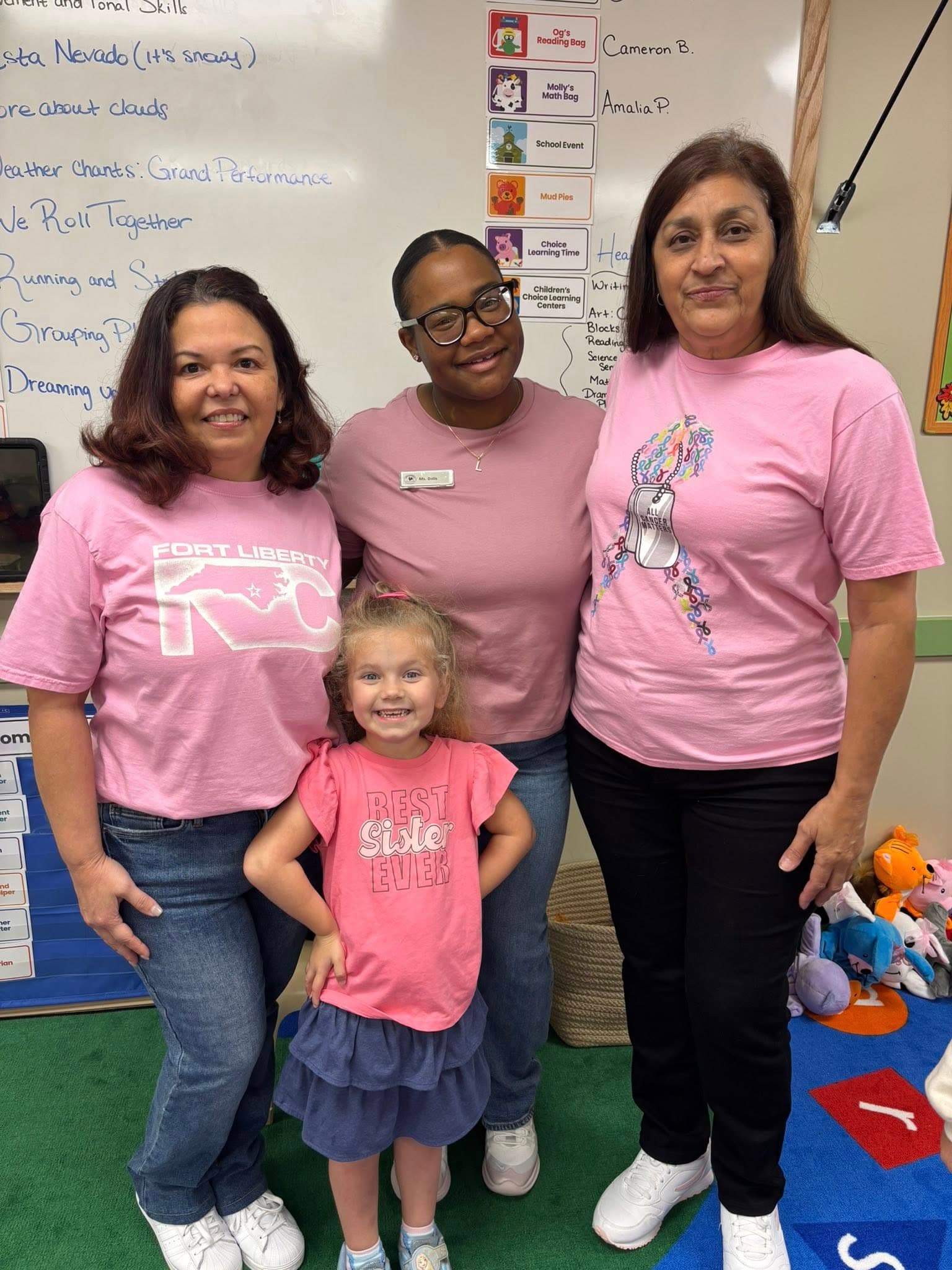 three adult women and a girl in pink shirts and jeans