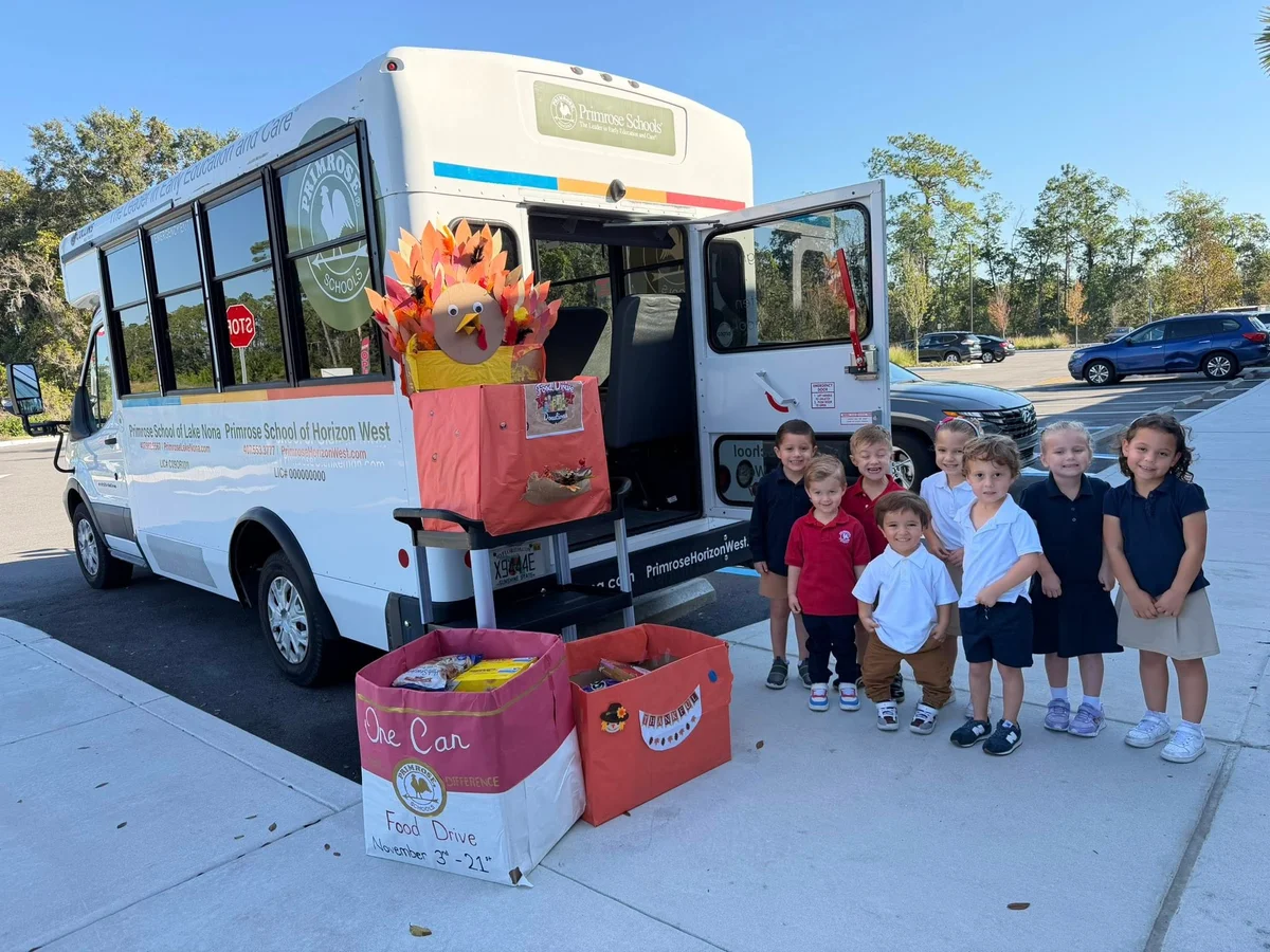 group of children standing outside of a bus with boxes