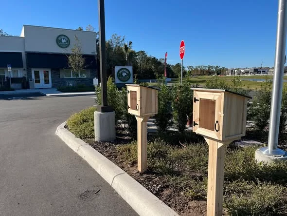 two wooden little libraries outside of a building