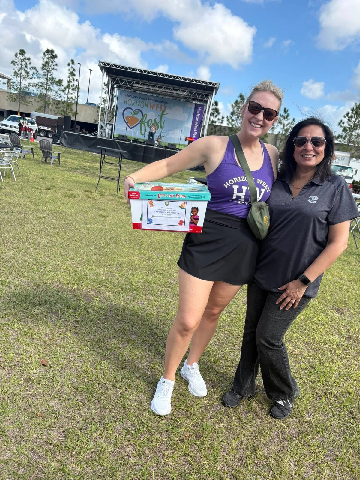 two women one in a purple shirt and one in a gray shirt in a field outside