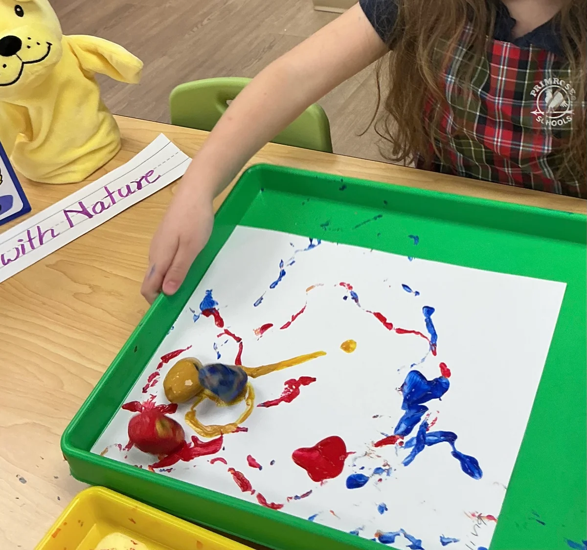 bin with art work being painted with a marble by a child