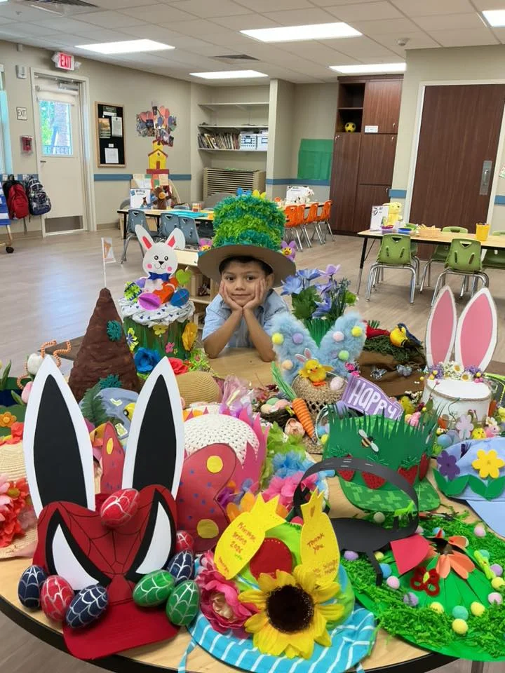 spring hats on a table with a child standing in the middle of them