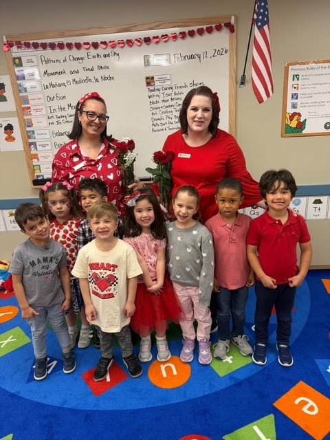 students in red and pink in front of two teachers in red