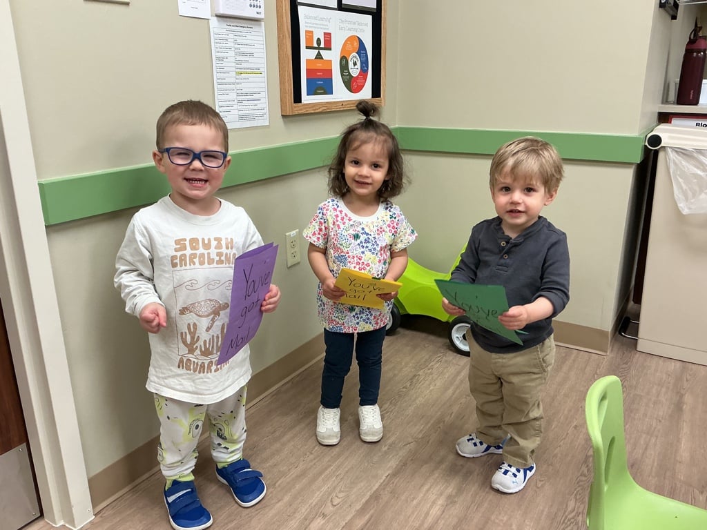 Three Primrose School of Forest Hill children sharing and displaying artwork in a Early Preschool classroom setting