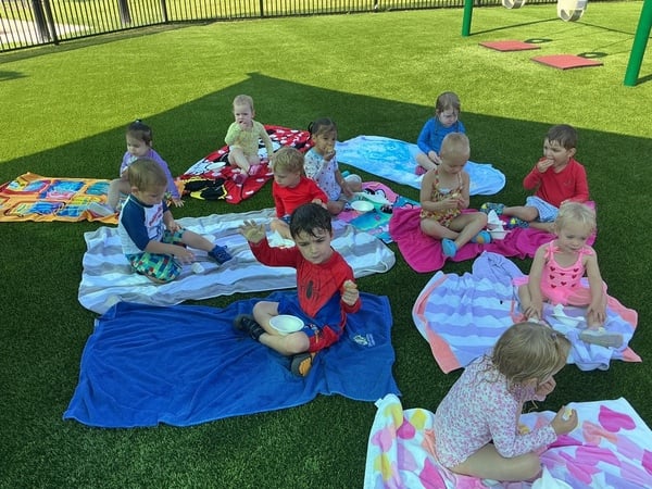 Children at Primrose School of Forest Hill enjoying Water Day with outdoor water play and a picnic, laughing, splashing, and making summer memories with friends.