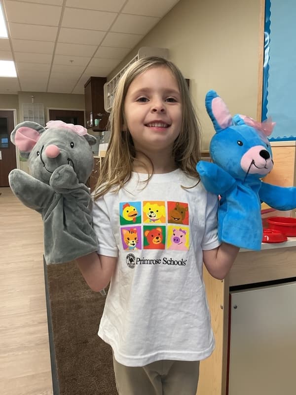 Child engaging in dramatic play center with Mia and Ally Primrose Friend puppets in Pathways Classroom at Primrose School of Forest Hill classroom