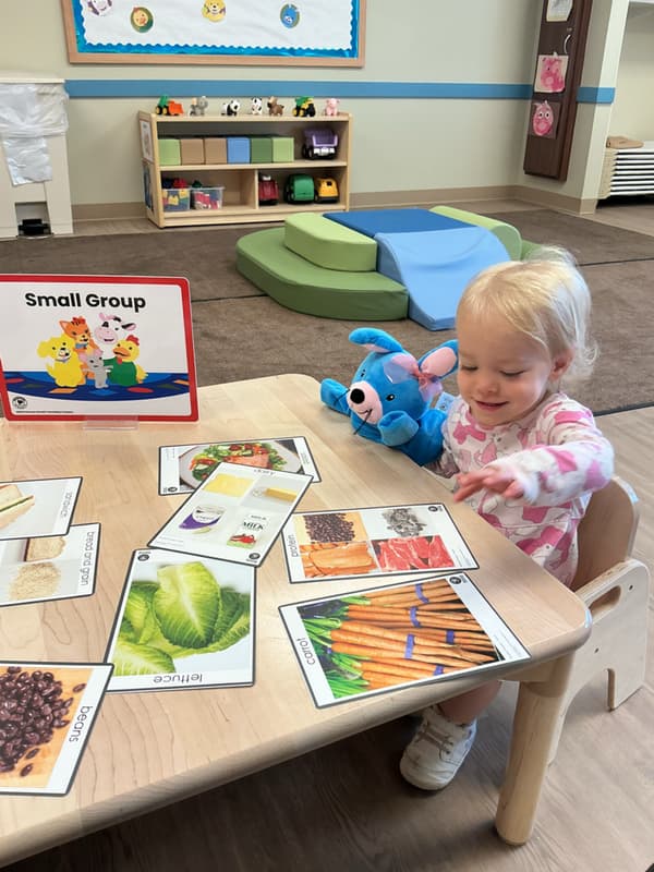 Preschool child participating in a small group learning activity with a Primrose Friend Character at Primrose School of Forest Hilll