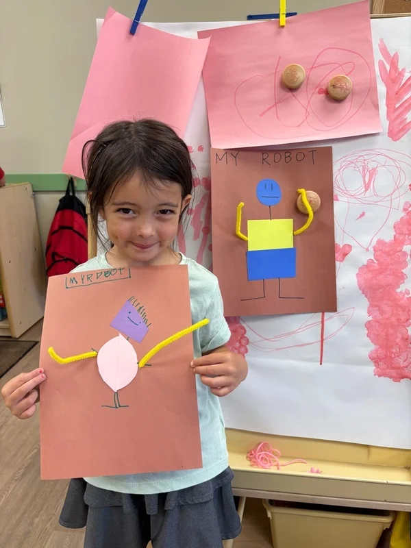 child holding a robot art project