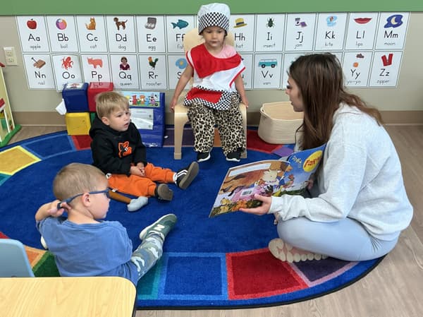 Teacher leading circle time with preschool students gathered on the classroom rug during a Primrose learning activity