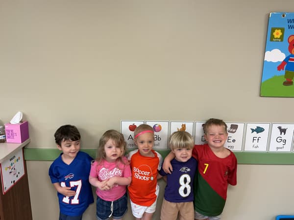 A group of young children at Primrose School of Forest Hill smiling together, showing friendship and school pride in a cheerful classroom setting.