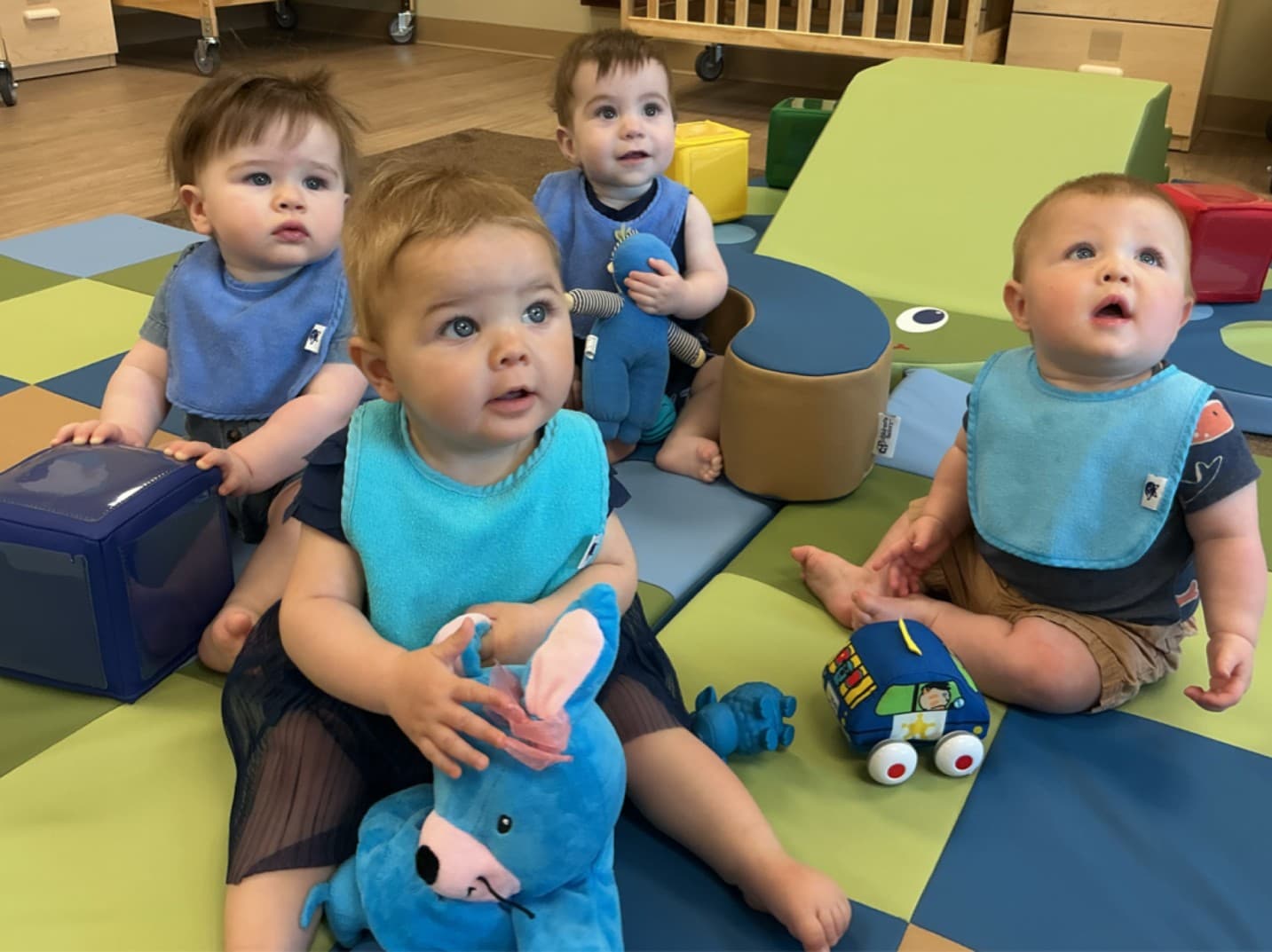 Infants at Primrose Forest Hill sitting on a soft classroom mat engaging with bright color‑sorting materials to build early thinking skills.
