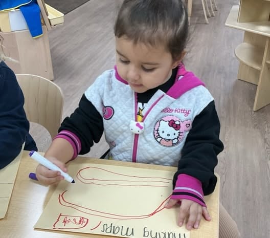 Toddler using a marker to practice early writing and drawing while strengthening fine motor skills and creativity at Primrose School.