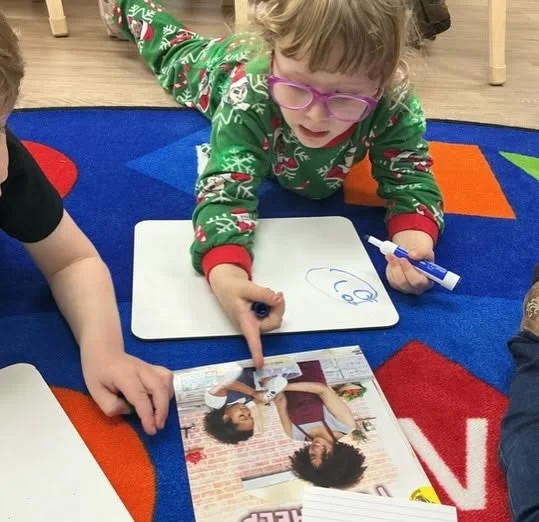 Preschooler using a family photo during a classroom activity that encourages communication, vocabulary development, and social-emotional learning at Primrose School.