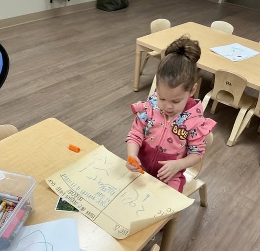 Toddler creating colorful marks with a marker during an early writing activity that supports creativity, hand-eye coordination, and fine motor development at Primrose School.