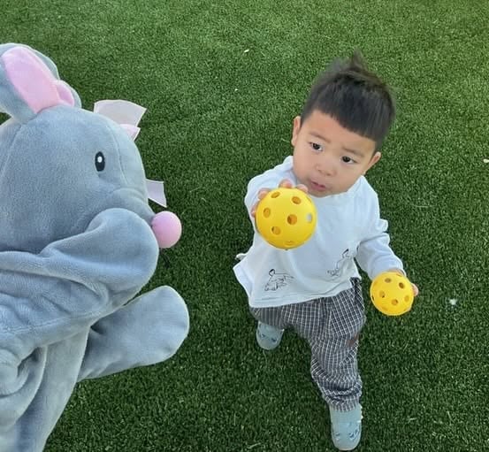 Toddler holding playground balls while enjoying active outdoor play that supports gross motor development, coordination, and confidence at Primrose School.
