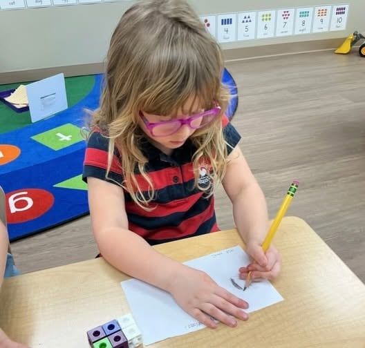 Preschooler practicing early writing and pencil grip during a hands-on literacy activity that strengthens fine motor skills and letter formation at Primrose School.