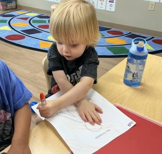 Toddler using a marker to practice early writing and drawing while strengthening fine motor skills, creativity, and hand-eye coordination at Primrose School.