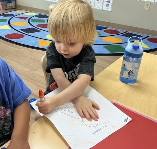 Toddler using a marker to practice early writing and drawing while strengthening fine motor skills, creativity, and hand-eye coordination at Primrose School.