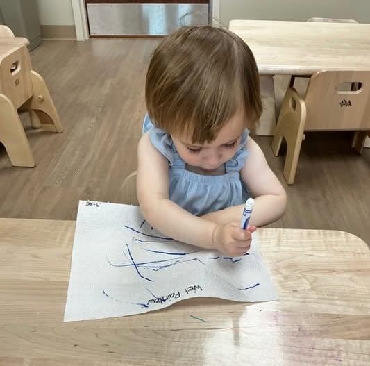 Toddler practicing early writing and fine motor skills by drawing with a marker during a hands-on learning activity at Primrose School.