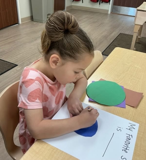 Preschooler completing a creative classroom activity that combines drawing, coloring, and early writing to encourage self-expression and fine motor development at Primrose School.