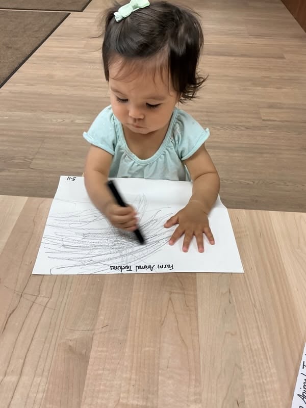 Toddler using a marker to create early drawings while strengthening hand-eye coordination, fine motor skills, and creativity at Primrose School.