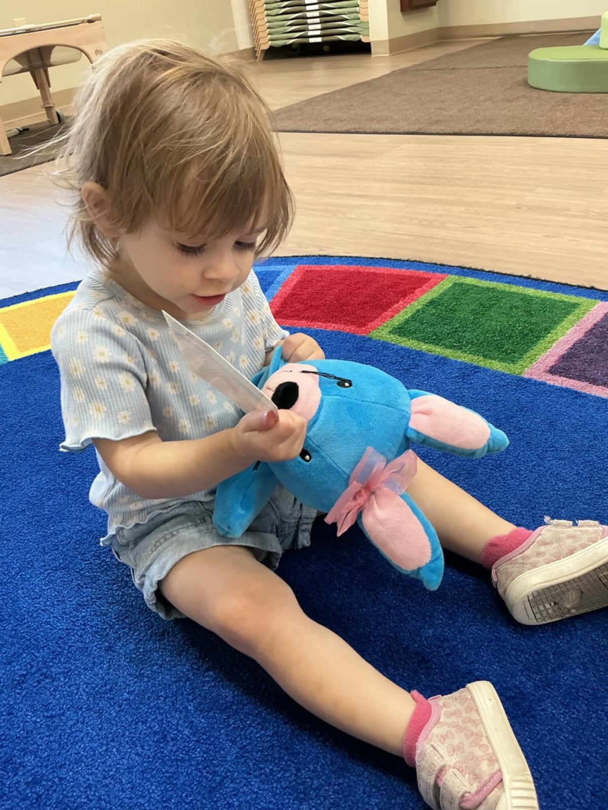 Toddler enjoying imaginative play while caring for a classroom plush friend, encouraging creativity, language development, and social-emotional learning at Primrose School.