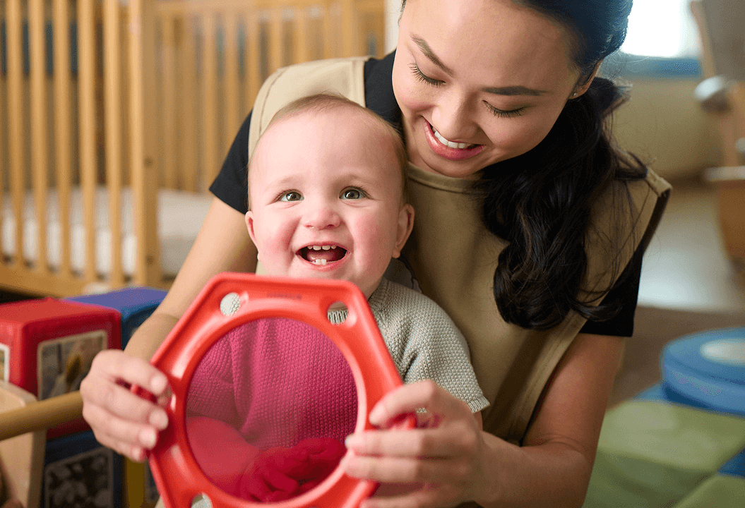 Daycare teacher showing infant a mirror