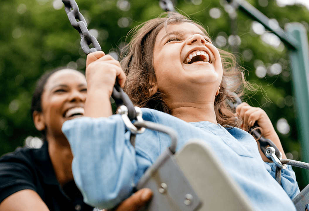 primrose teacher pushing a preschool child on the swing