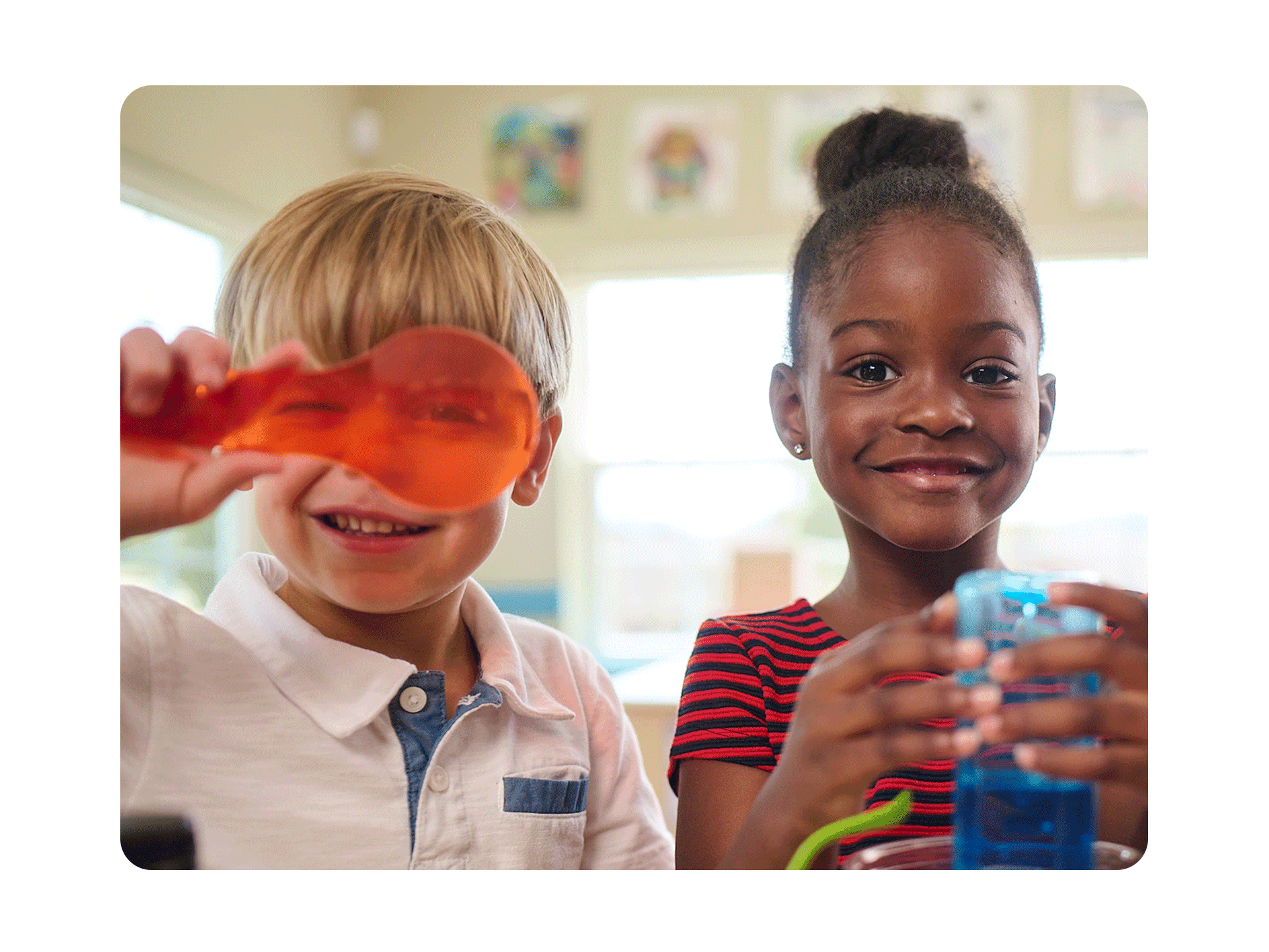 Primrose students looking into magnifying glass and smiling at camera