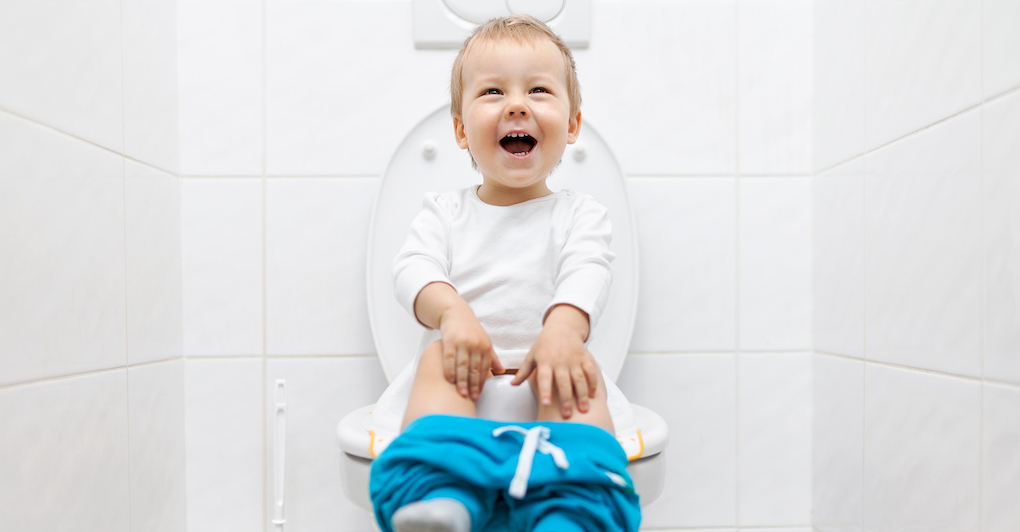 Child smiles and sits on toilet