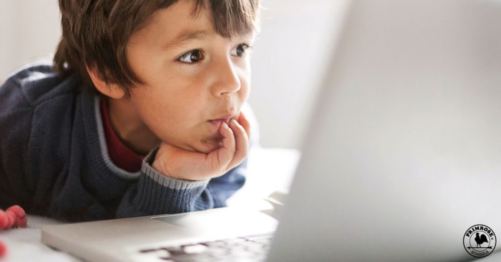 A young boy engaged in watching a video on a computer