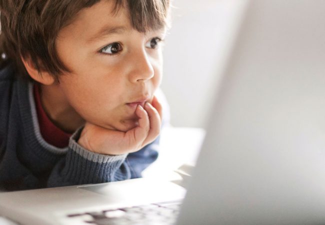 A young boy engaged in watching a video on a computer