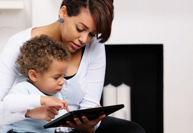 A mother teaching her young son with the help of a tablet
