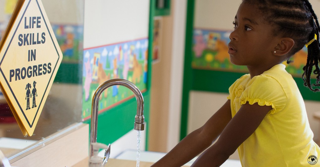 A primrose student washes her hands before meal time