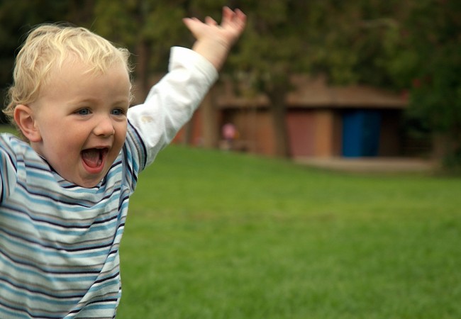 A happy toddler running outdoors