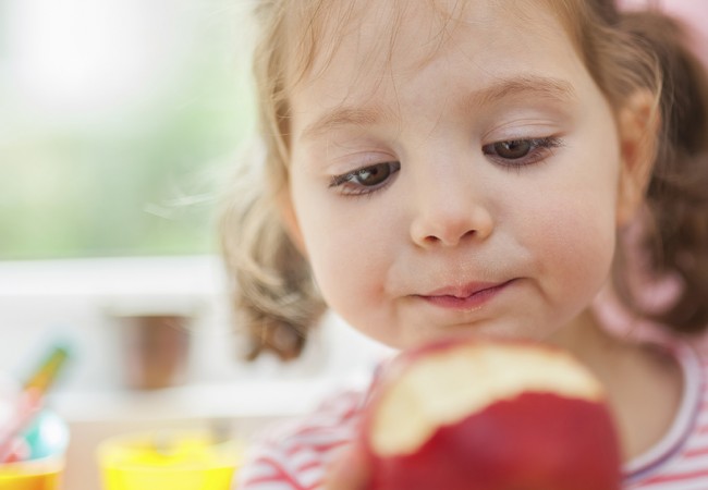 A little girl eating an apple
