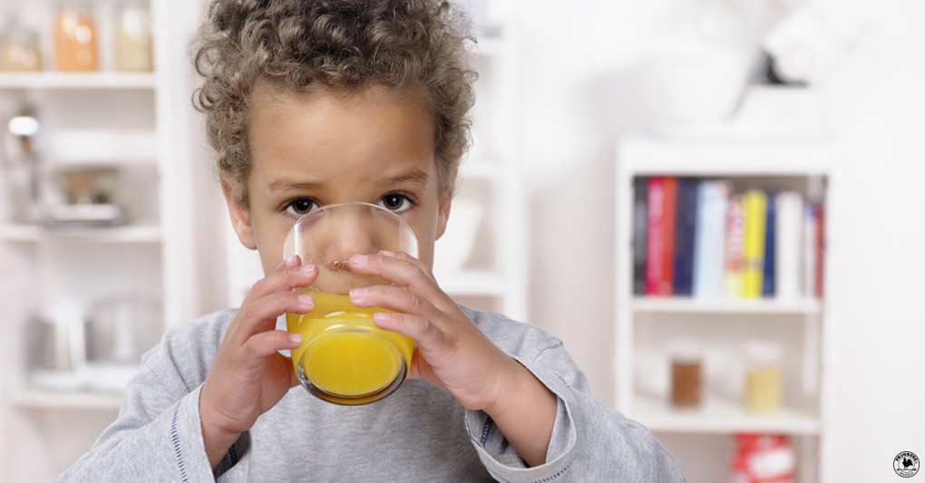 A little boy drinking a glass of orange juice
