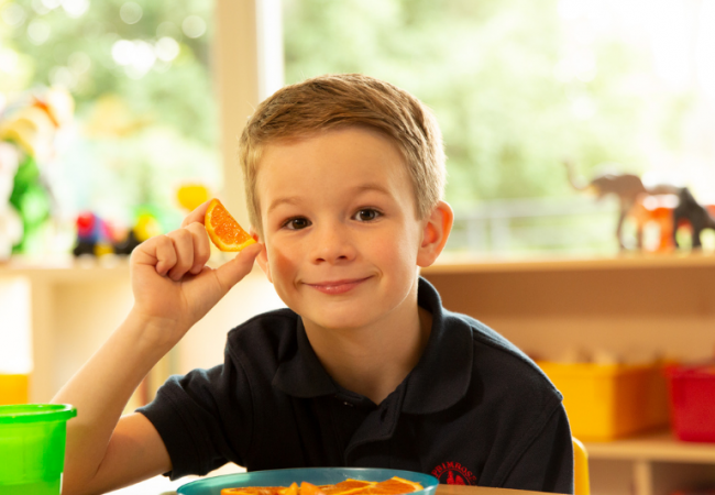 Boy smiling holding an orange