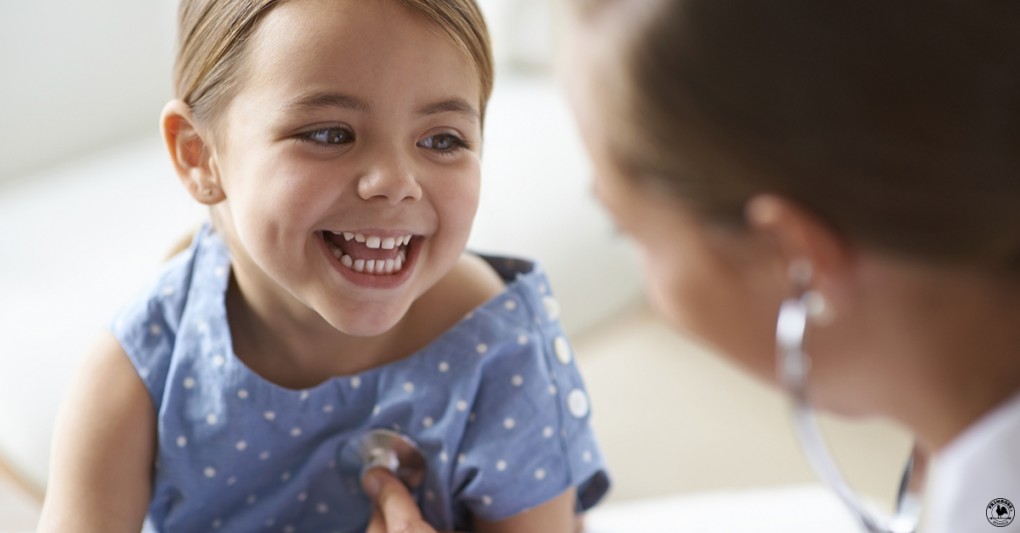 Little girl smiling as the doctor checks her heart beat with a stethoscope