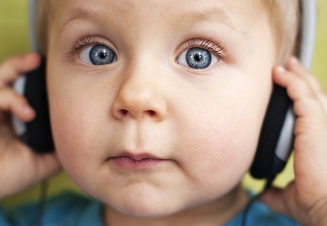 Little boy looks surprised as he listens to music on a pair of headphones
