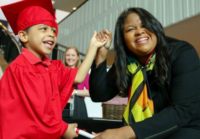 A mother smiles ecstatically as her little son graduates from Primrose school