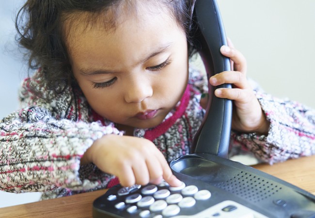 A little girl practices dialing a number in case of an emergency