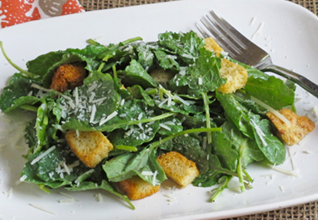 A salad make with kale and croutons, sprinkled with cheese